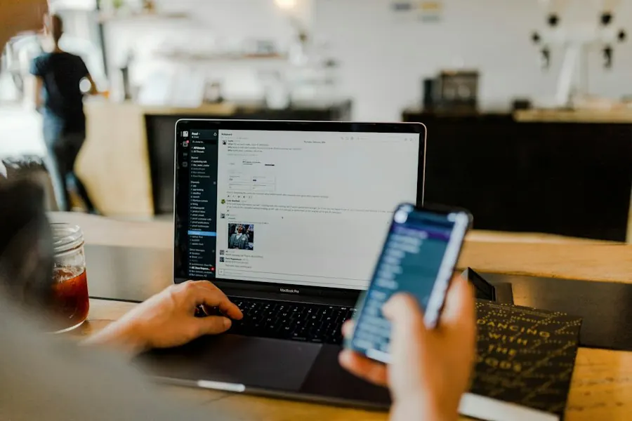 Person using a phone in front of a laptop